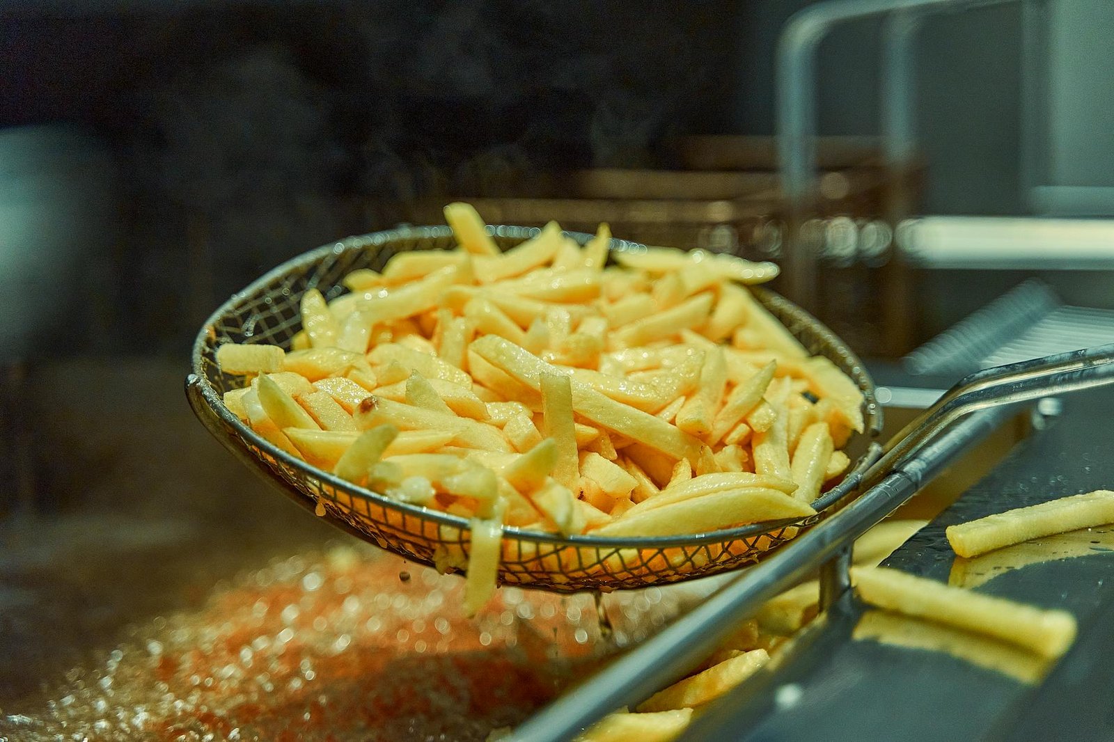 Cestello di una friggitrice ad aria con patatine dorate e croccanti pronte da servire