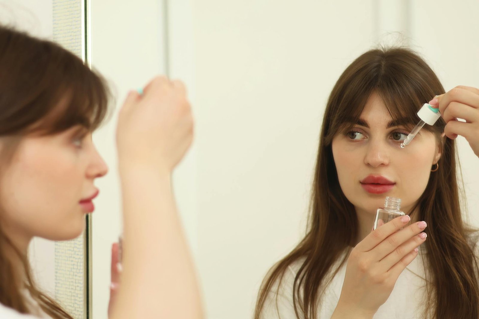 Donna che applica un siero sul viso davanti allo specchio